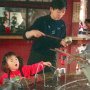 Kyoto, Japan. Girl and mother drinking from communal fountain.
